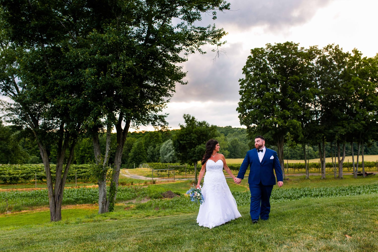 Bride and groom walking together during sunset at Two Hearts Vineyard overlooking Magnanini Winery