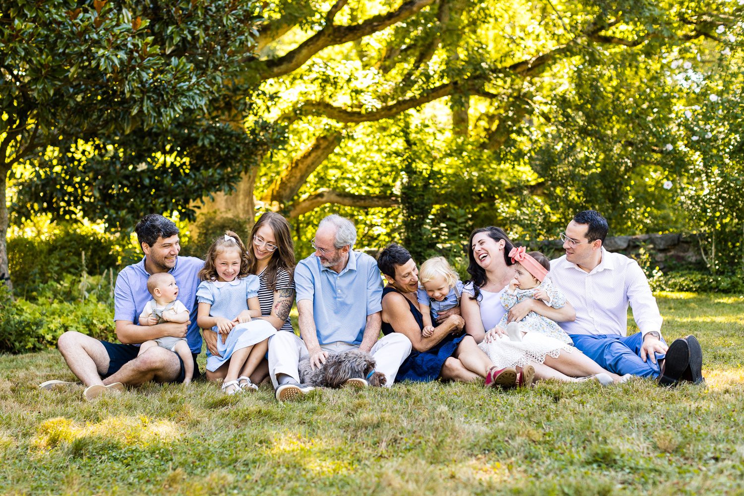 Candid extended family photo, sitting on the grass laughing and smiling with each other